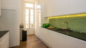 Une cuisine moderne avec des armoires blanches, un plan de travail noir et un pare-feu vert.