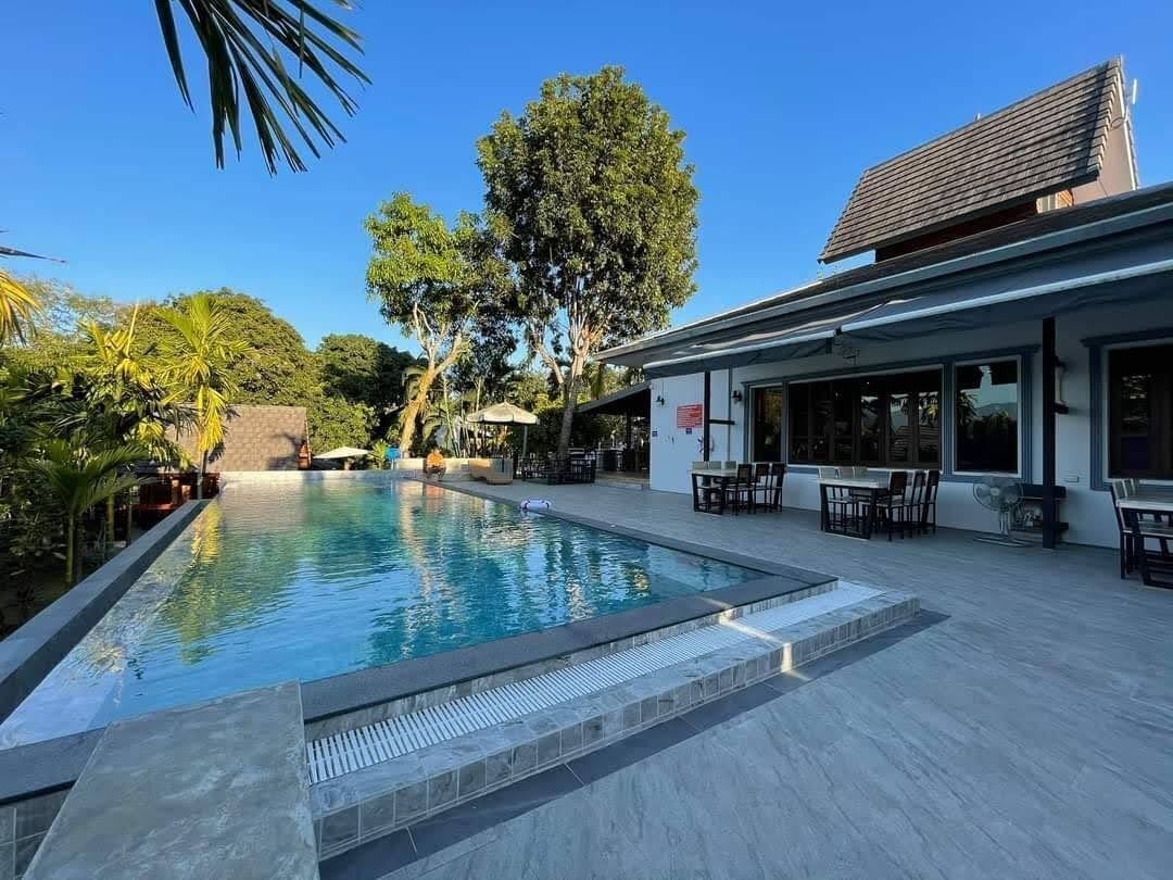 A swimming pool with a patio area, outdoor seating, and a building with large windows.
