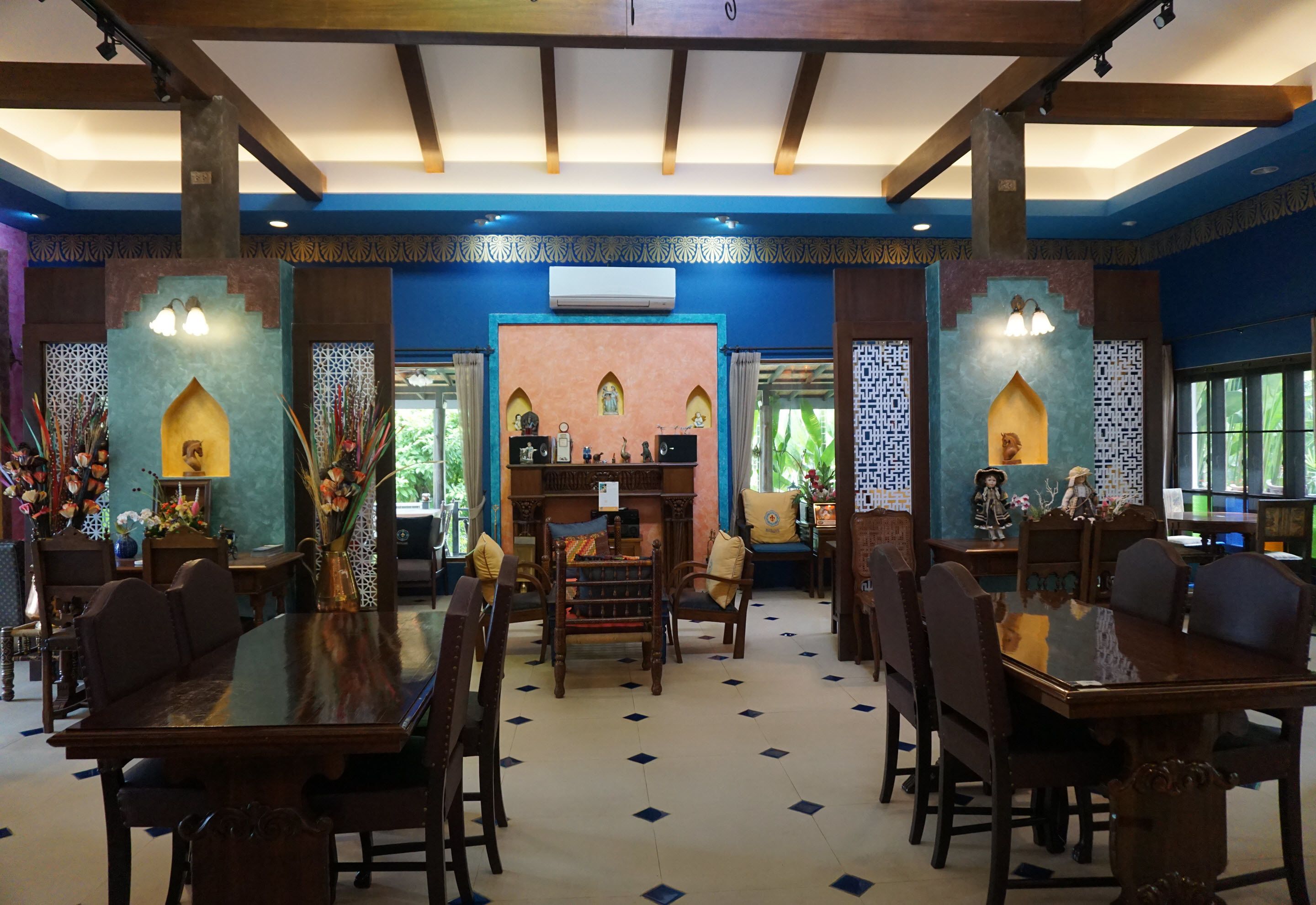 Comedor con mesas y sillas de madera, paneles decorativos en la pared y un equipo de aire acondicionado.