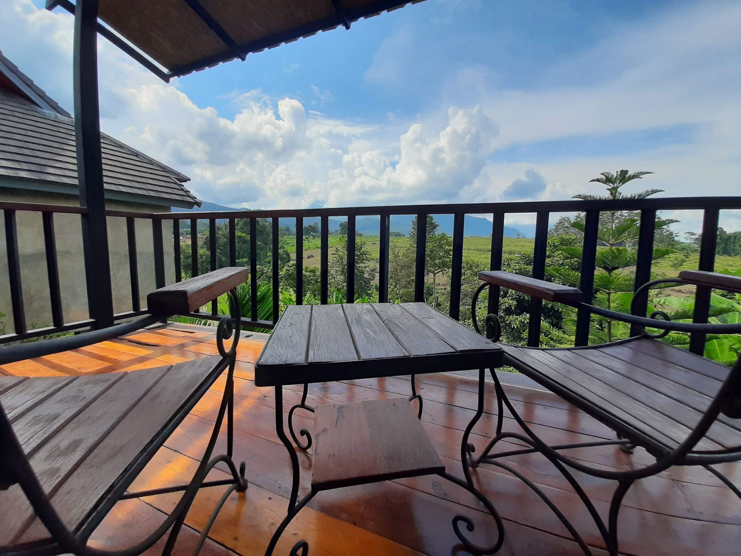 A wooden deck with a table and two chairs, overlooking a lush landscape.