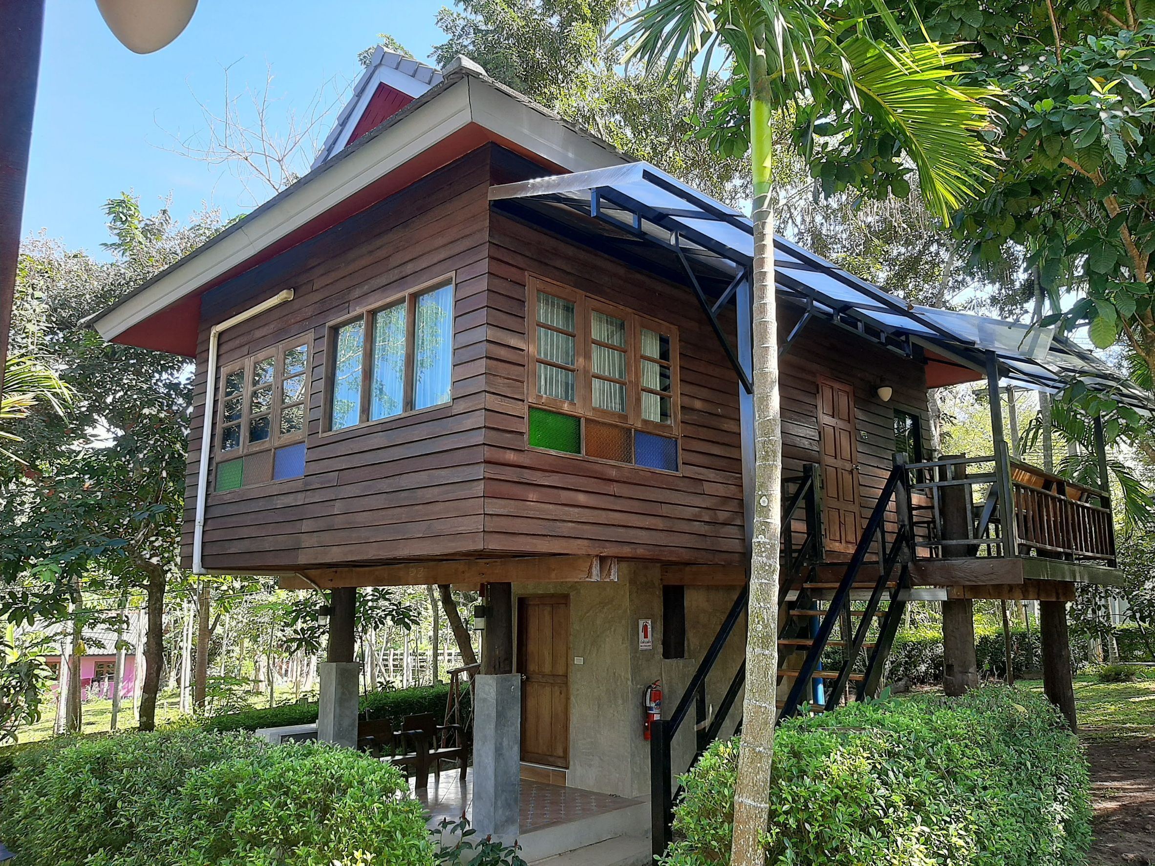 Una casa de madera con balcón, rodeada de follaje.