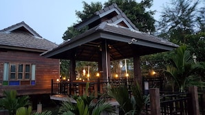 A wooden building with a covered patio area featuring outdoor seating and string lights.