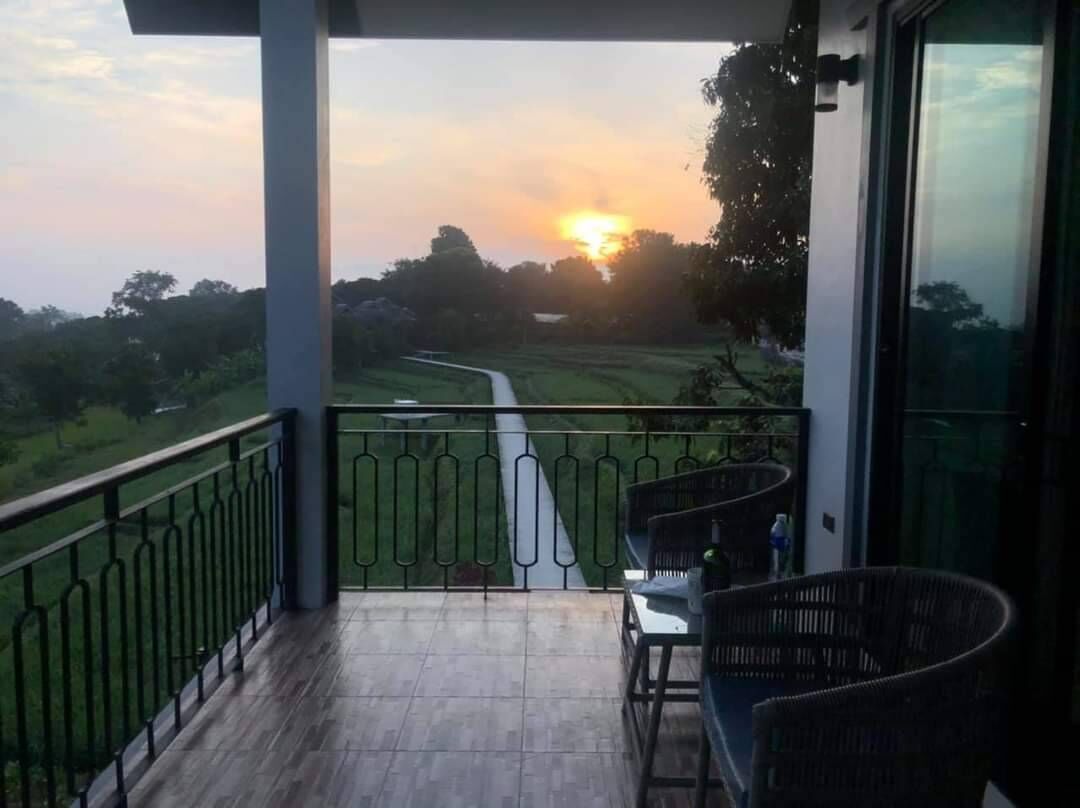 A balcony with a view of a sunset over a green landscape.