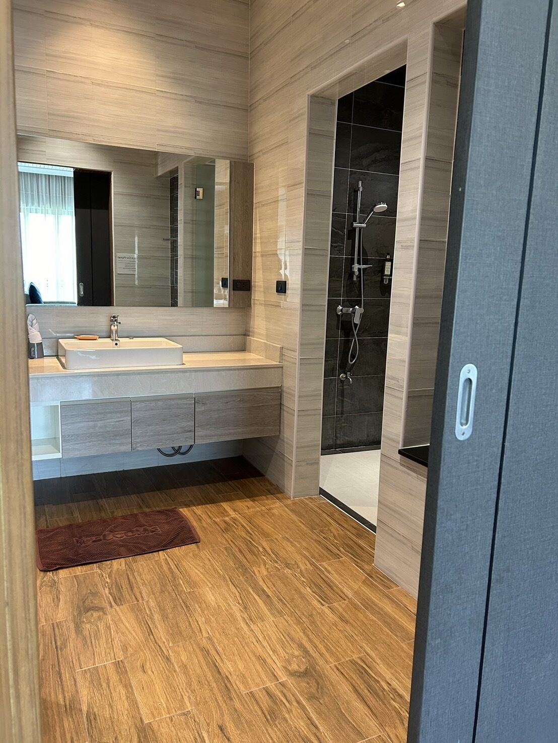 Ein modernes Badezimmer mit großem Spiegel, Waschbecken und Duschbereich.