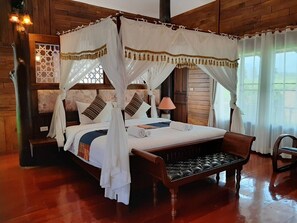 A four-poster canopy bed with a wooden headboard, a bench at the foot of the bed, and a nightstand with a lamp. - Buraphat Resort (Chiang Dao)