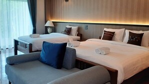 A hotel room with two beds, a sofa, and a lamp.