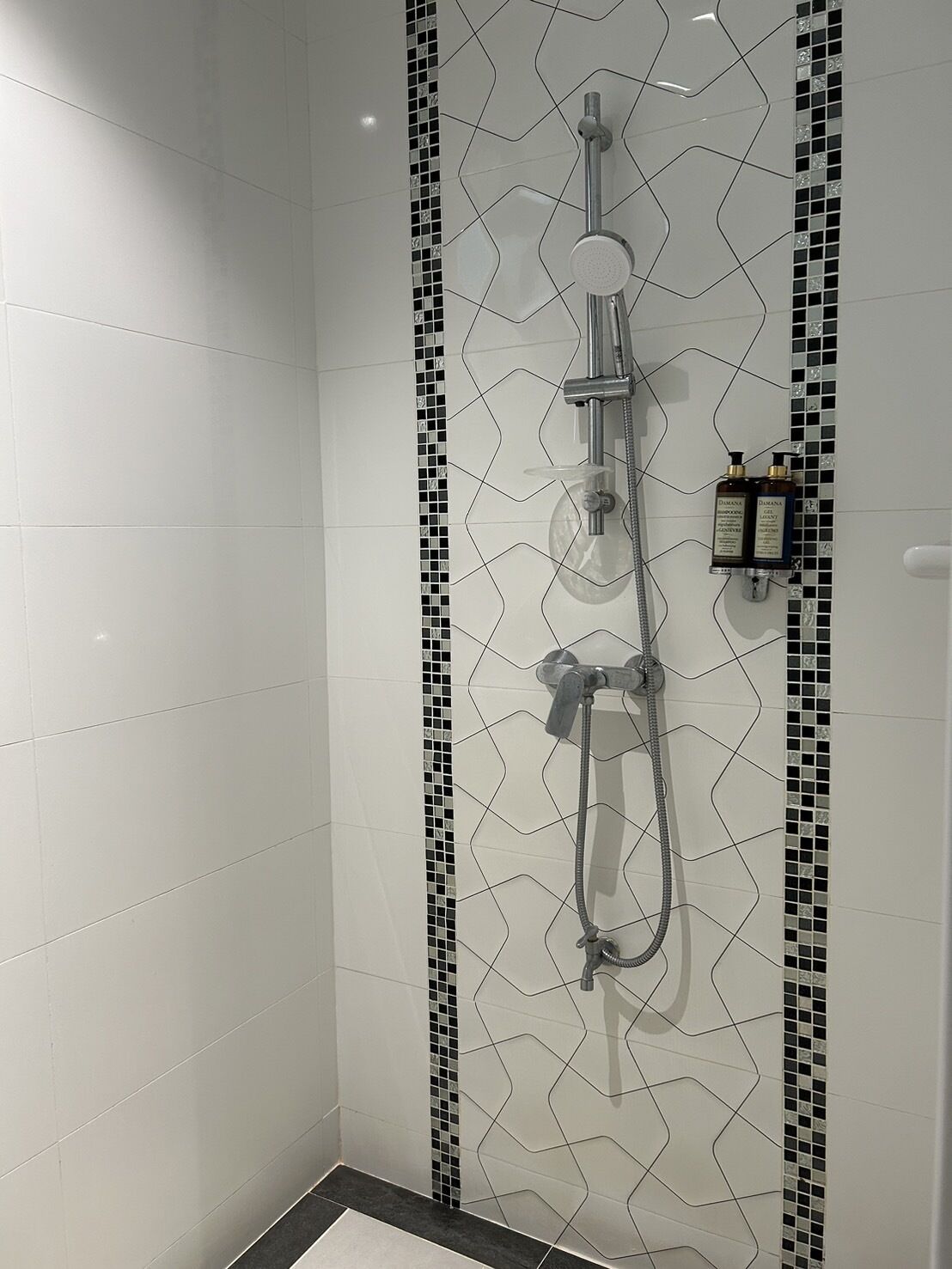 A shower area with a geometric tile pattern and a handheld showerhead.