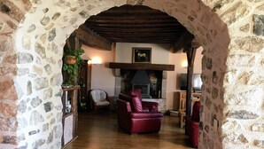 A stone-walled room with a fireplace, leather sofa, and wooden flooring. - Farmhouse for 15 people, swimming pool, SPA, billiards, air conditioning (Luzy)