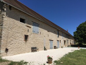 A stone building with multiple windows and doors, a gravel driveway, and a bench. - Farmhouse for 15 people, swimming pool, SPA, billiards, air conditioning (Luzy)