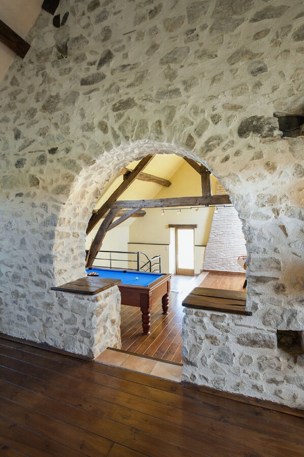A stone-walled room with a wooden floor, a pool table, and a staircase leading to an upper level. - Farmhouse for 15 people, swimming pool, SPA, billiards, air conditioning (Luzy)