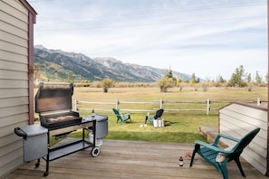 Una terraza con una parrilla, sillas y vistas a las montañas.