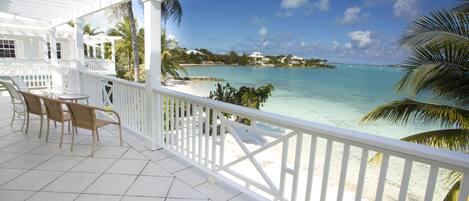 A covered outdoor area with white railings, a tiled floor, and wicker furniture.