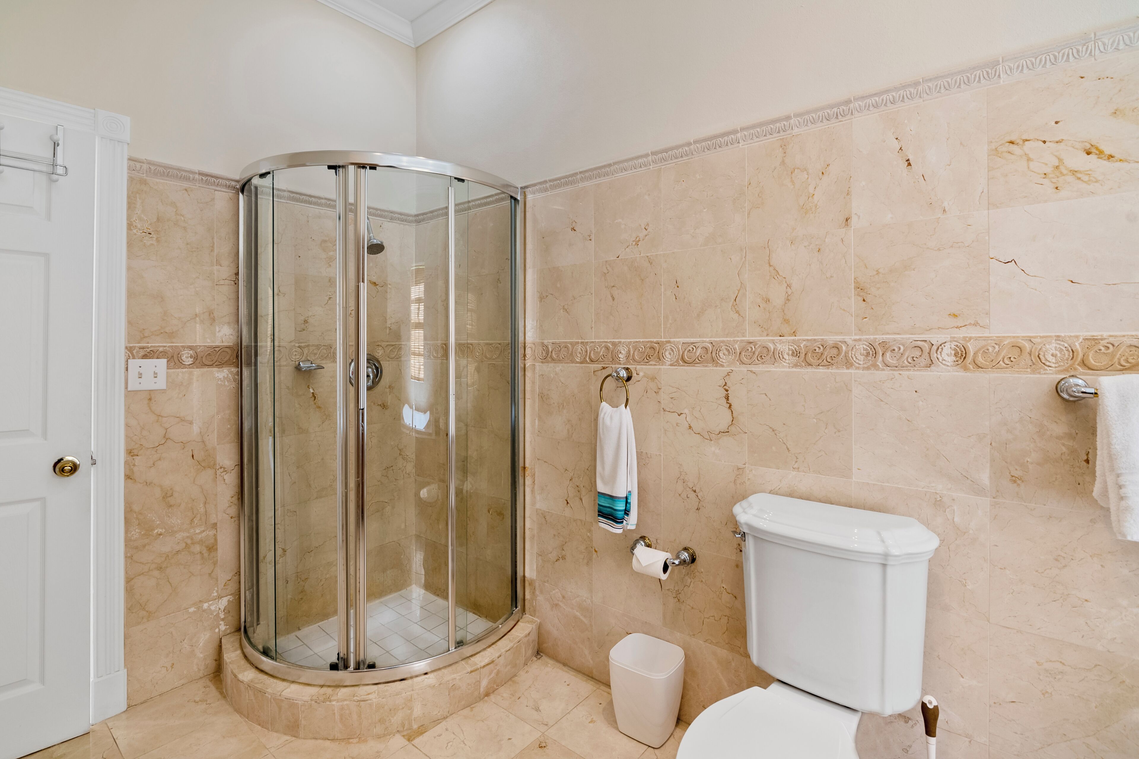 A bathroom with a glass-enclosed shower, a toilet, and a sink.