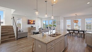 A spacious kitchen with a central island, large windows, and a dining area with a bench.