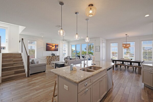 A spacious kitchen with a central island, large windows, and a dining area with a bench.