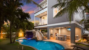 A modern two-story house with a swimming pool, outdoor bar, and patio furniture.