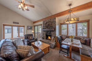 A cozy living room with a stone fireplace, leather furniture, and large windows. - Fresh interior, excellent location in Aspens (Wilson)