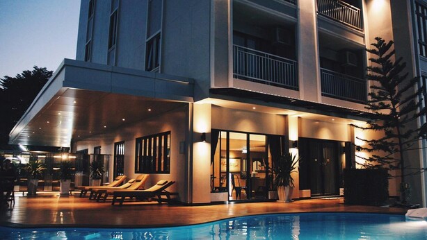 Ein modernes Hotel mit Schwimmbad, Außenbereich zum Entspannen und mehreren Balkonen.