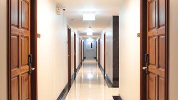 A hotel corridor with wooden doors, a marble floor, and a ceiling light.