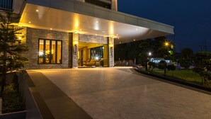 Ein moderner Hotel Eingangsbereich mit überdachtem Außenbereich, einer Rezeption und einem sichtbaren Hinweisschild für das Hotel.