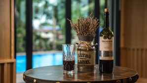 Eine Flasche Trivento Argentina Malbec Wein, ein Weinglas mit Rotwein und ein Etikett im Vintage-Stil auf einem runden Holztisch. Im Hintergrund ist ein Schwimmbad zu sehen.