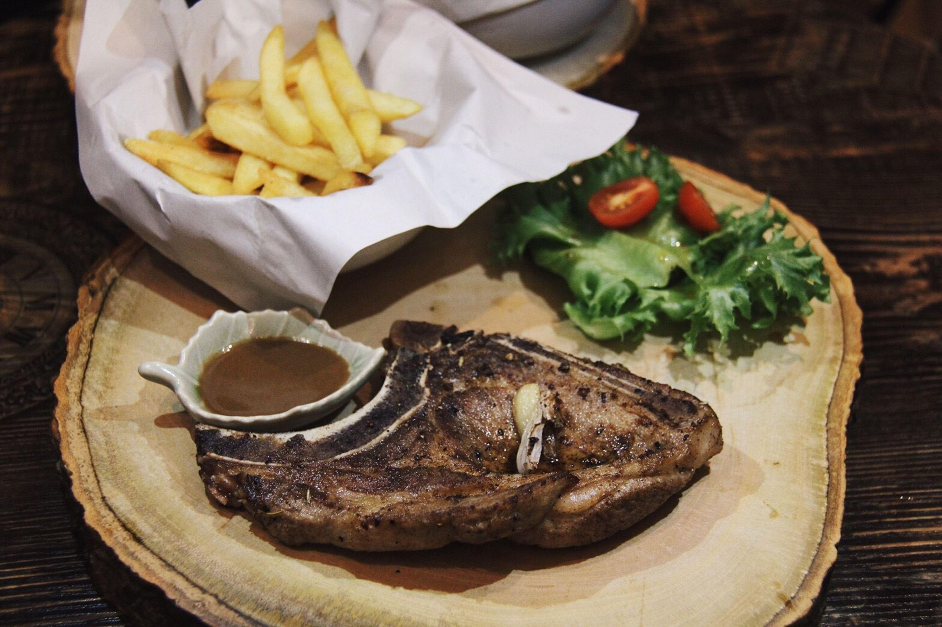 Un plato de carne con salsa, papas fritas y una ensalada.