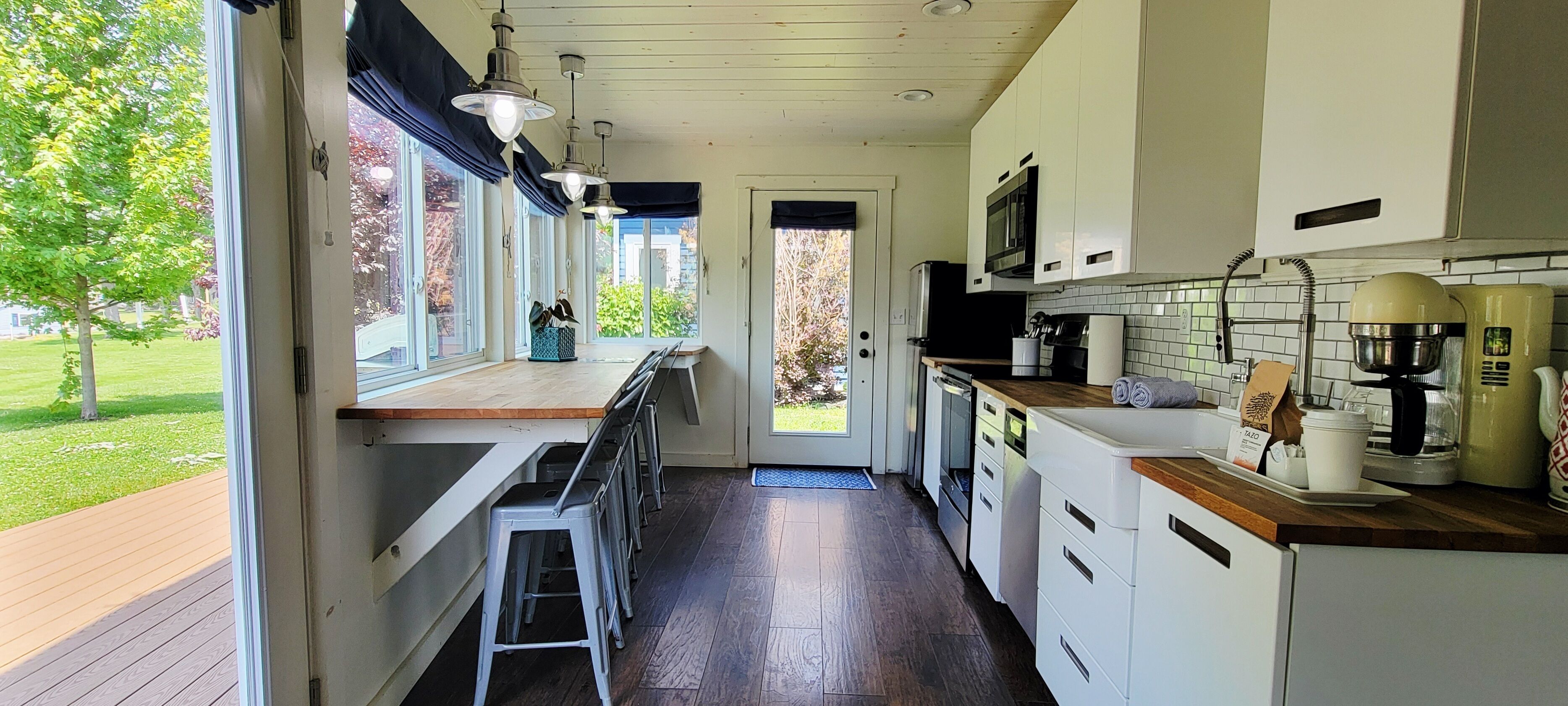 Una cocina con encimera de madera, armarios blancos y vistas al exterior.