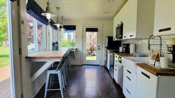 Una cocina con encimera de madera, armarios blancos y vistas al exterior.