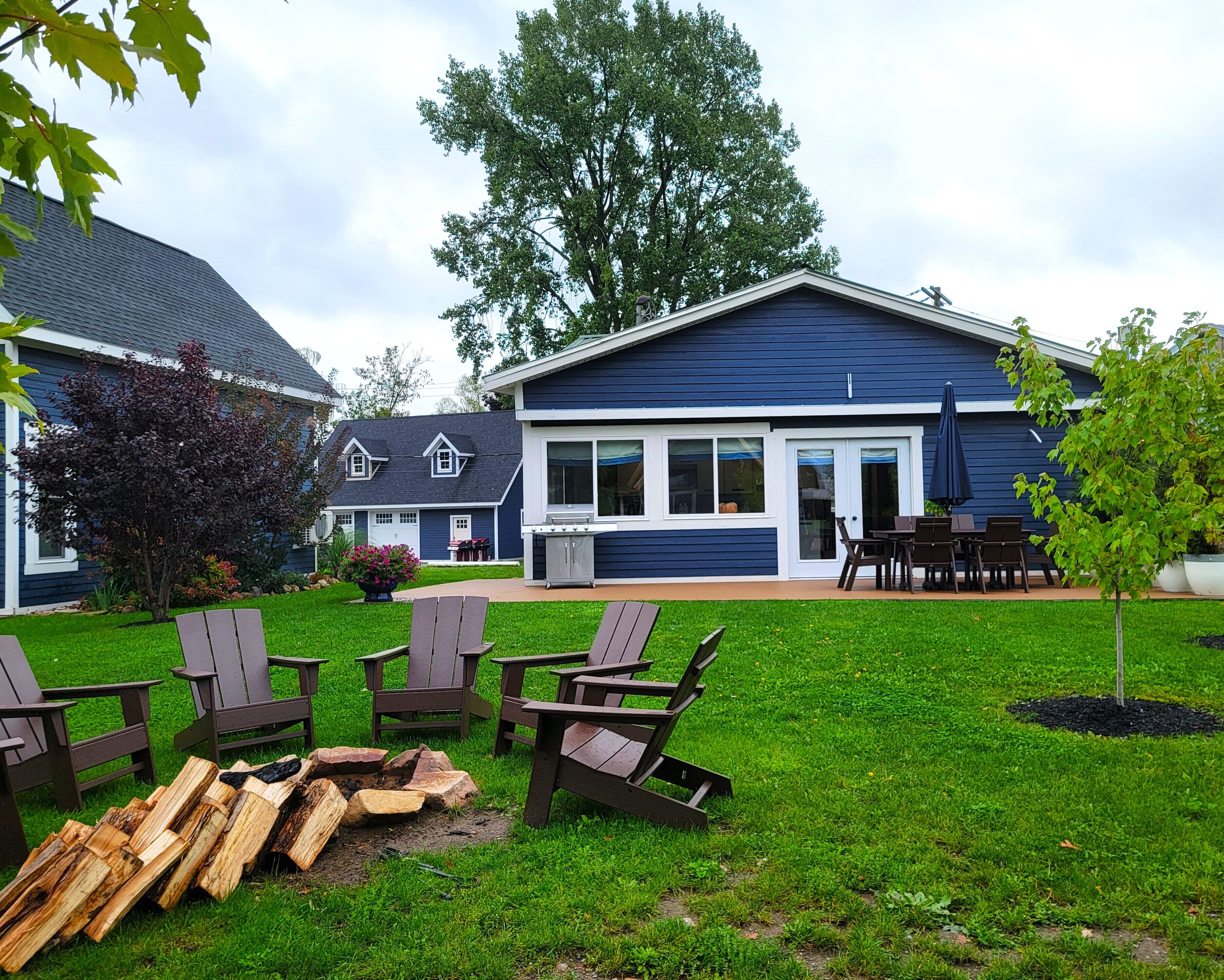 A residential property with a well-maintained lawn, outdoor seating area, and a barbecue setup.