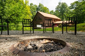 Situated in a lush forest, this cabin features a cozy fire pit and inviting porch.