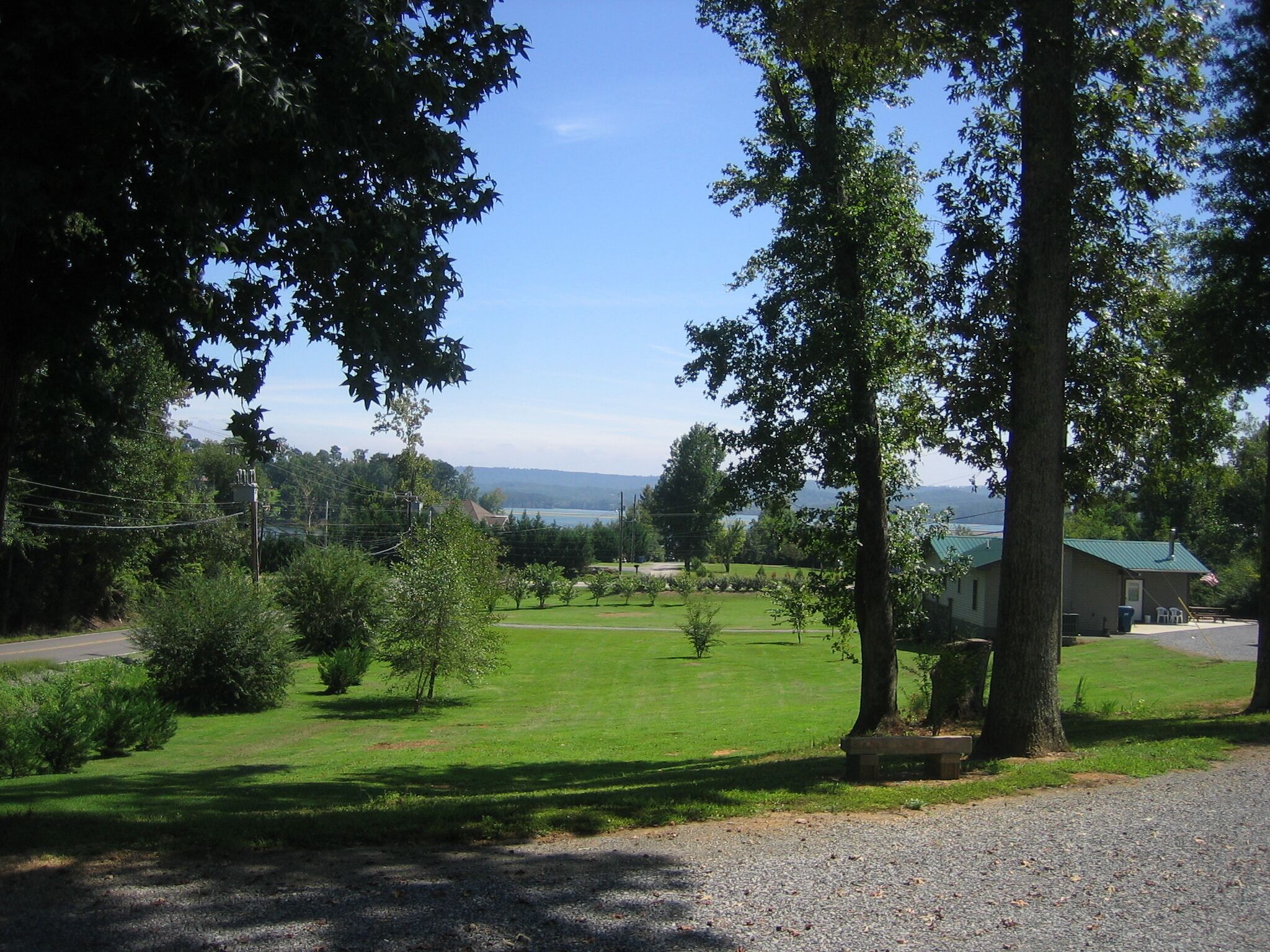 A grassy area with a building, trees, and a clear sky.