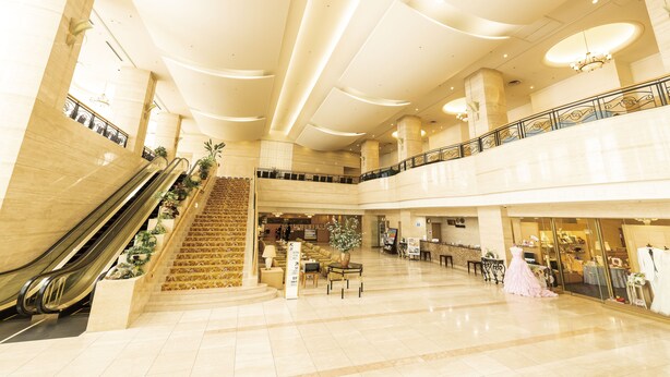 A spacious lobby with a central staircase, escalators, and a seating area.