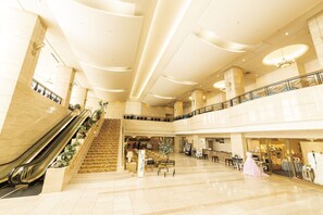 Un vestíbulo amplio con una escalera central, escaleras mecánicas y una zona de estar.