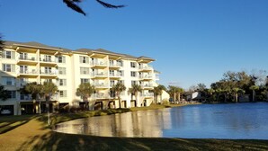 Un hotel de varios pisos con balcones y un extenso cuerpo de agua al frente.