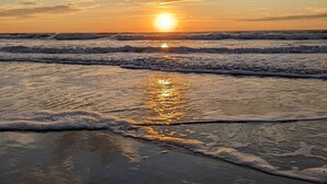 Una playa con olas y un atardecer.