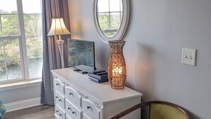 Una habitación con un aparador blanco, un espejo, una lámpara y una silla.