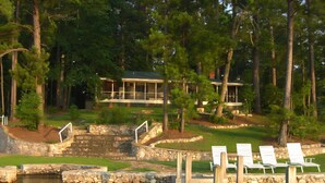 A lakeside property with a dock, stone steps, and white lounge chairs. - Aubreys Lakewood Cabin -FREE DAY w Qualified Booking- Fishing, Football Friendly (Eclectic)