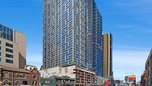 Un edificio alto de fachada moderna de vidrio, rodeado de otros edificios.