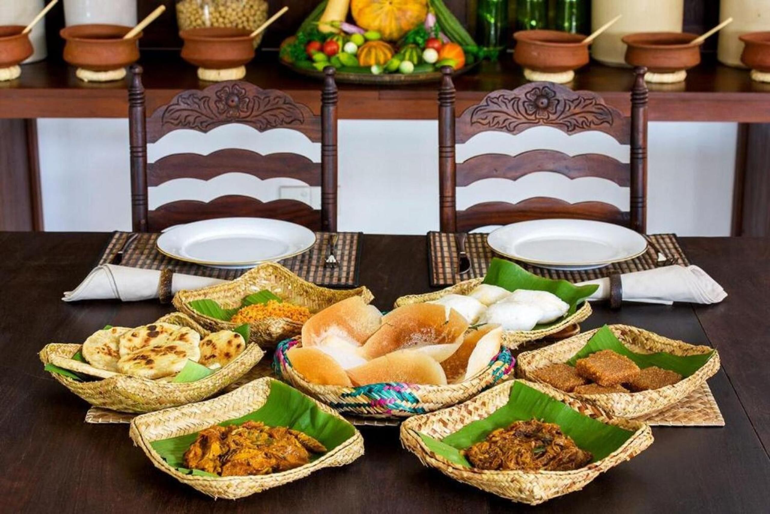 Una mesa de comedor con diversos alimentos en cestas tejidas, un centro de mesa decorativo y cerámica tradicional.