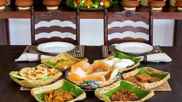 Una mesa de comedor con diversos alimentos en cestas tejidas, un centro de mesa decorativo y cerámica tradicional.