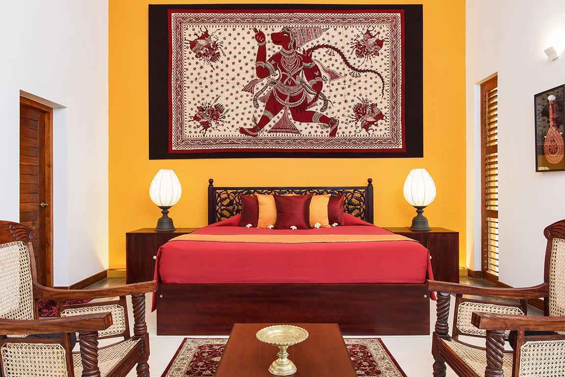 Una habitación con una cama, dos mesitas de noche, dos lámparas y un tapiz decorativo en la pared.