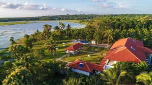 A resort with multiple buildings, a swimming pool, and a large body of water. - The Notary's House (Pannala)