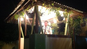 A small, enclosed structure with a roof supported by wooden beams, surrounded by lush greenery. - Danel Pensionne House (Tacloban)