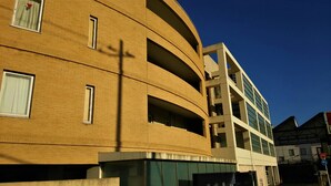 Un edificio de varios pisos con fachada curva, ventanas grandes y techo plano.