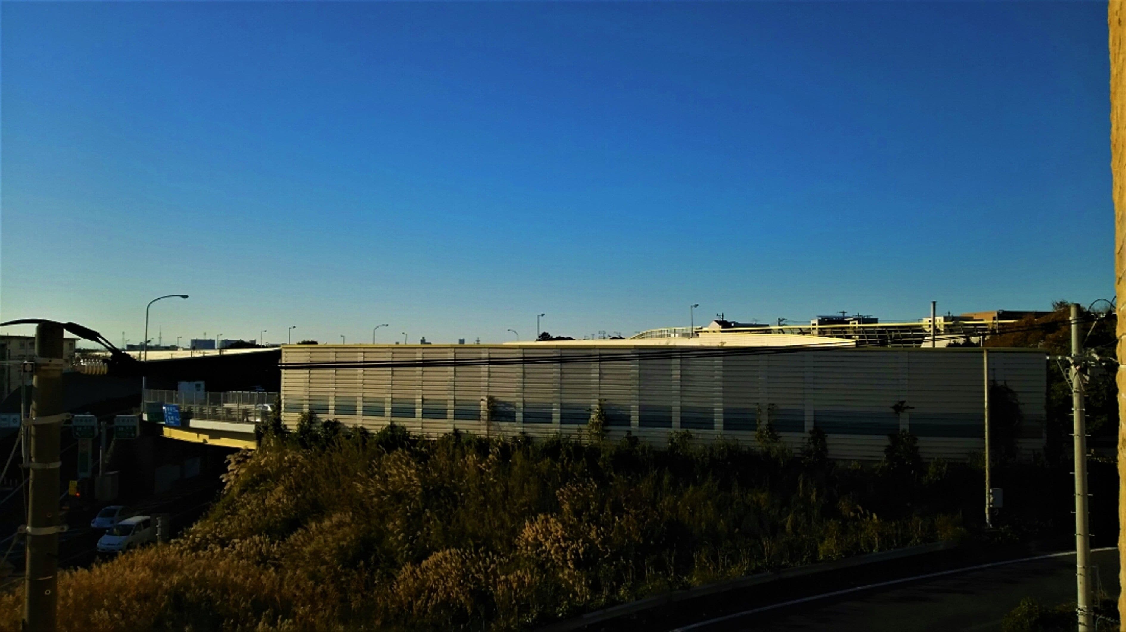 A large industrial building with a flat roof and a long, narrow structure.
