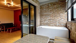 A modern bathroom with a stone wall, a white bathtub, and a bench. - Ulsan Hotel 109 (Ulsan)