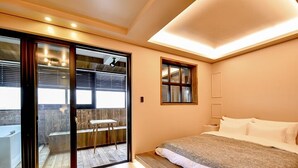 A bedroom with a large bed, a sliding glass door leading to a balcony, and a small table. - Ulsan Hotel 109 (Ulsan)