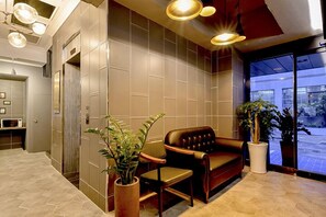 A modern lobby with a leather sofa, potted plants, and a large window offering a view of the street. - Ulsan Hotel 109 (Ulsan)