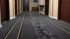 Un pasillo de hotel con pisos alfombrados, puertas de madera y un televisor montado en la pared.