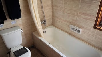 A bathroom with a toilet, a bathtub, and a shower curtain.